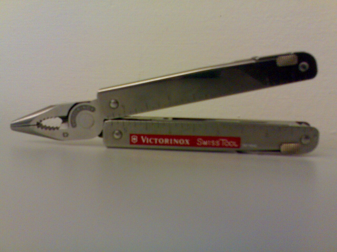 Stainless Victorinox SwissTool with pliers open and side implements extended