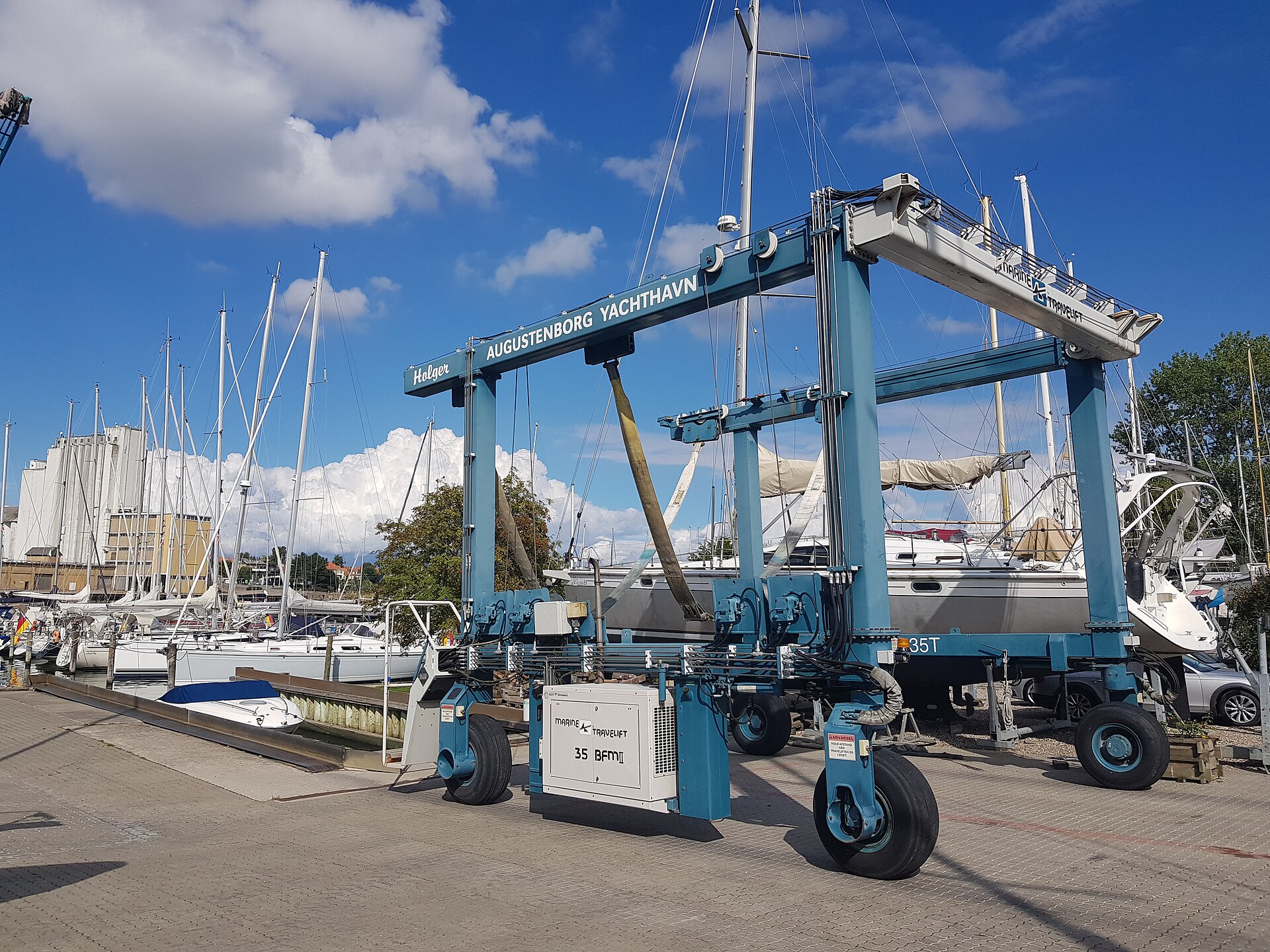 A sailboat hauled out and supported in the slings of a travel lift at a boatyard