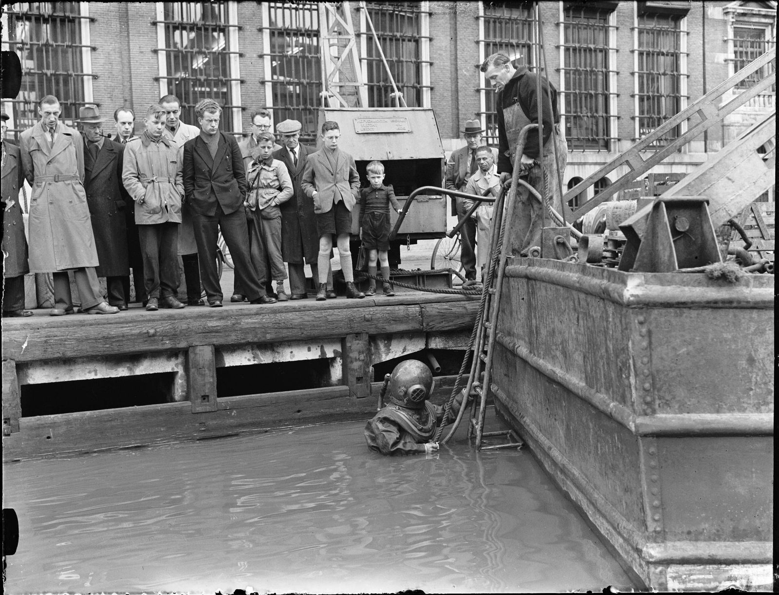 Historic photograph of a surface-supplied diver being tended from a boat