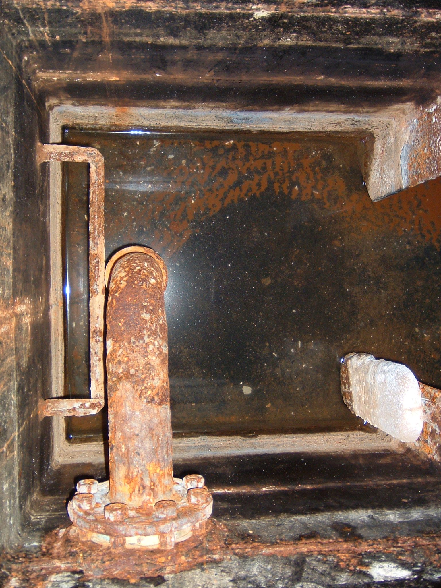 An open bilge well showing pump plumbing and hose fittings inside a boat's hull